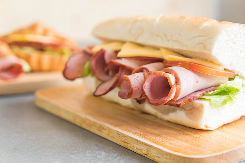 Ham and salad submarine sandwich on table background